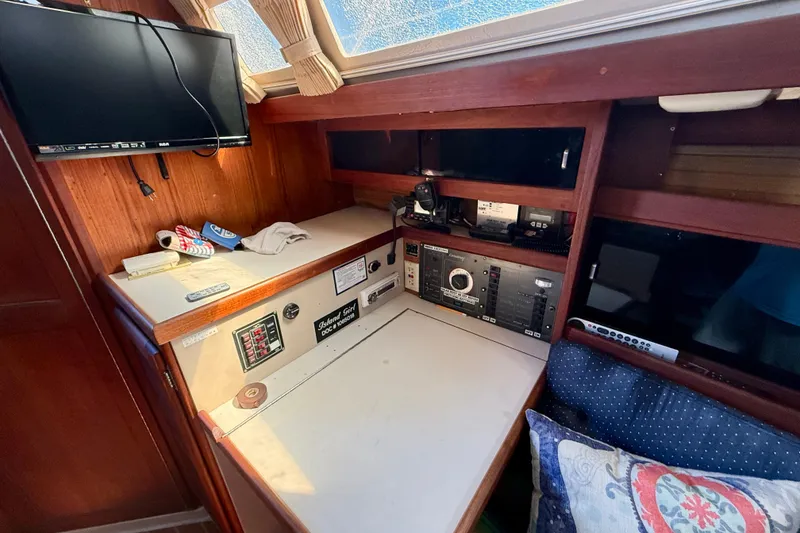 Slide: The Image of Navigation station inside a 1988 Catalina 34 sailboat with control panels and a mounted TV. - 19
