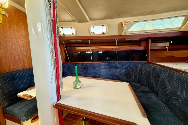 Slide: The Image of Interior of a 1988 Catalina 34 sailboat with a cozy dining area and blue upholstery. - 21