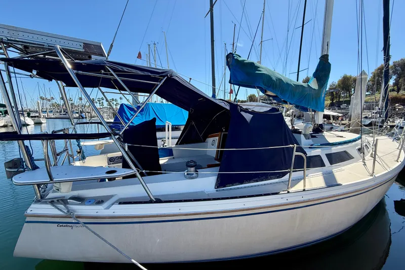 Slide: The Image of 1988 Catalina 34 sailboat docked in marina, featuring blue canvas covers and sleek design. - 3