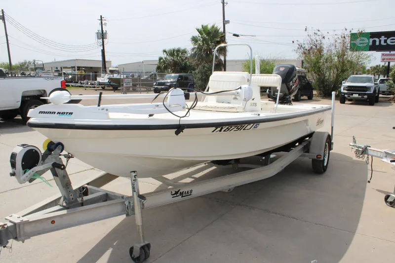 Slide: The Image of 2014 Mako 18 LTS boat on trailer, parked outdoors, featuring Minn Kota motor. - 4