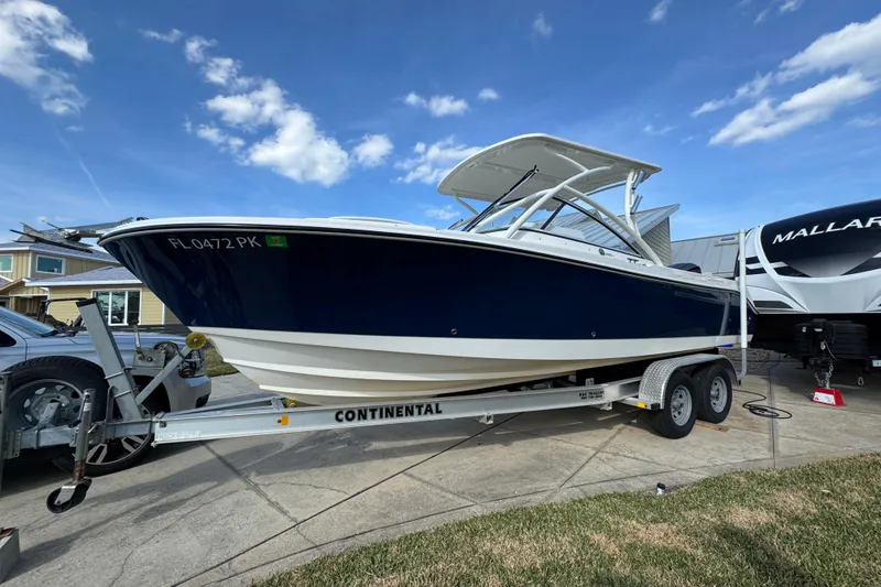 The Image of 2012 Edgewater 245CX Crossover boat on trailer, parked outdoors under blue sky. - 0