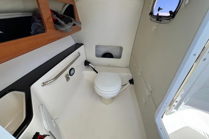 Slide: The Image of Interior of 2012 Edgewater 245CX Crossover boat featuring a compact marine toilet. - 15