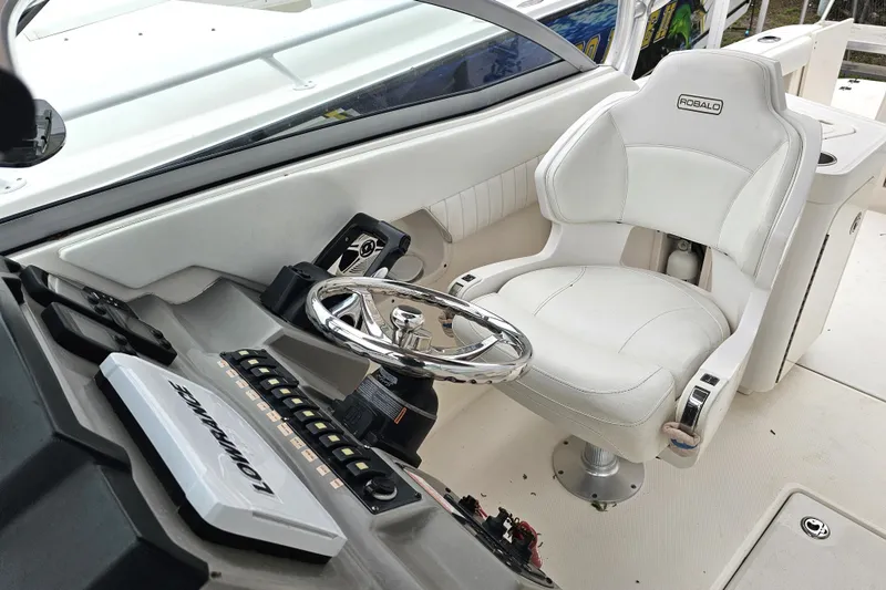 Slide: The Image of 2013 Robalo R247 Dual Console helm with white captain's chair and steering wheel. - 16