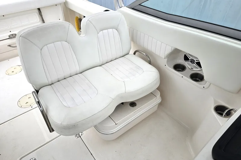 Slide: The Image of 2013 Robalo R247 Dual Console boat interior with white seating and cup holders. - 17