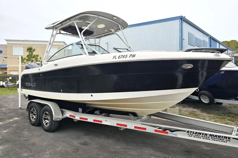 Slide: The Image of 2013 Robalo R247 Dual Console boat on trailer, parked outdoors. - 2