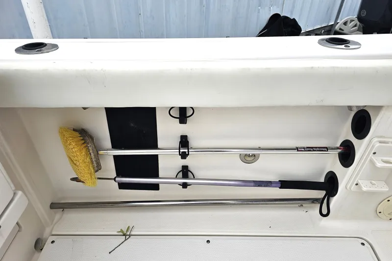 Slide: The Image of Storage compartment on a 2013 Robalo R247 Dual Console boat with cleaning tools. - 21