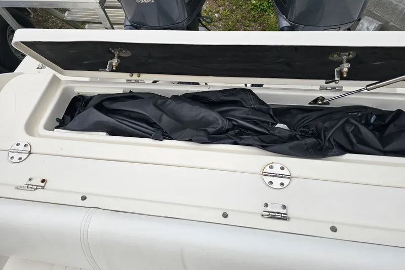 Slide: The Image of Open storage compartment on 2013 Robalo R247 Dual Console boat, showing black cover inside. - 32