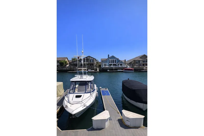 The Image of 2007 Boston Whaler 320 Outrage Cuddy Cabin docked in a serene waterfront setting. - 0
