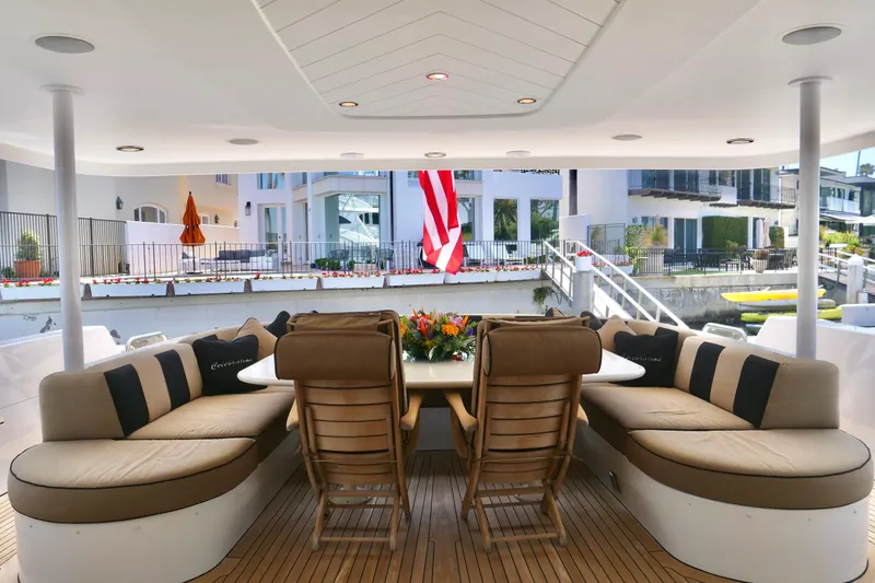 Slide: The Image of Luxurious Westport 112 yacht deck with elegant seating, table, and American flag, docked near waterfront homes. - 54
