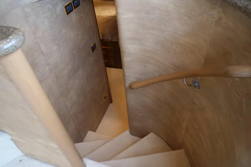 Slide: The Image of Curved staircase inside 2000 Westport 112 yacht with wooden handrail and carpeted steps. - 86