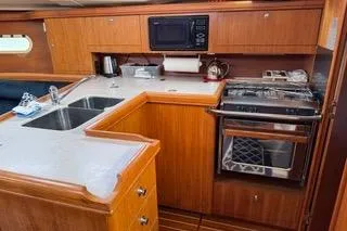 Slide: The Image of 2003 Hunter 356 yacht kitchen with wooden cabinetry, sink, stove, and microwave. - 10