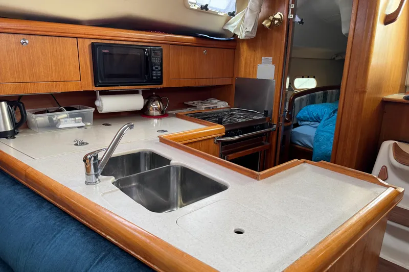 Slide: The Image of 2003 Hunter 356 yacht interior with kitchen, sink, stove, and microwave. - 14