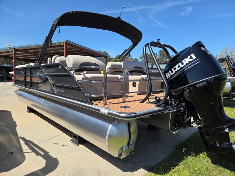 Slide: The Image of 2026 Bentley Pontoons Legacy Quad 243 with Suzuki engine, parked outdoors. - 2