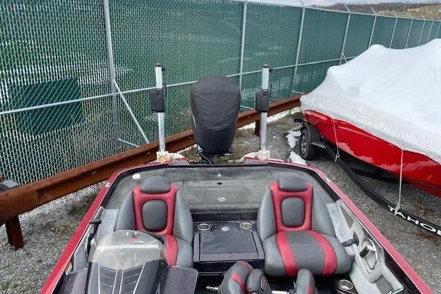 Slide: The Image of 2015 Ranger Z518 Cup-Equipped boat with red and gray seating, parked near a fence. - 3