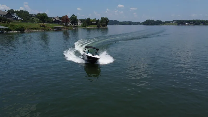 Slide: The Image of 2023 Sea Ray SLX 260 Surf boat cruising on a serene lake under a clear sky. - 10