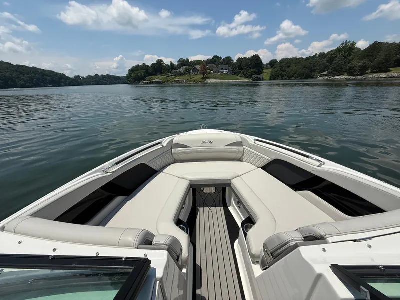 Slide: The Image of 2023 Sea Ray SLX 260 Surf boat interior on a calm lake with scenic shoreline. - 21