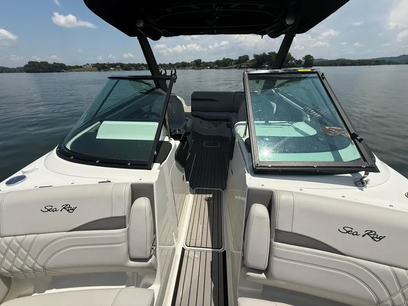 Slide: The Image of 2023 Sea Ray SLX 260 Surf boat interior with open windshield on a calm lake. - 25