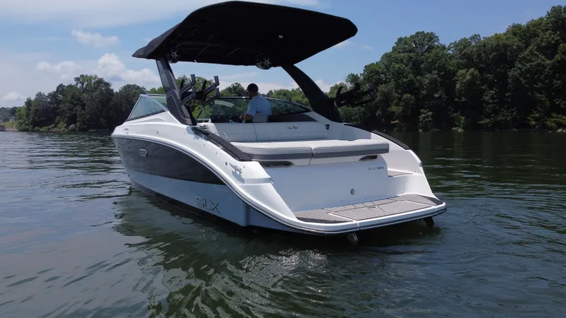 Slide: The Image of 2023 Sea Ray SLX 260 Surf boat on a calm lake with lush green trees. - 5