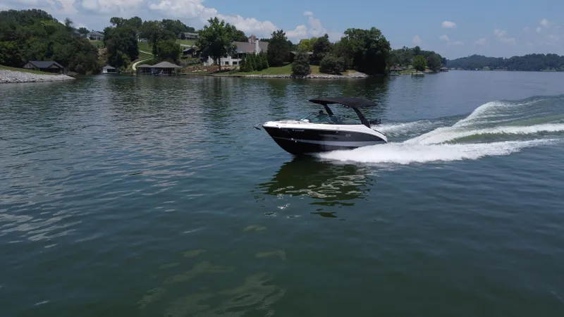 Slide: The Image of 2023 Sea Ray SLX 260 Surf boat cruising on a scenic lake. - 8