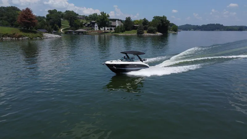 Slide: The Image of 2023 Sea Ray SLX 260 Surf boat cruising on a serene lake with scenic background. - 9