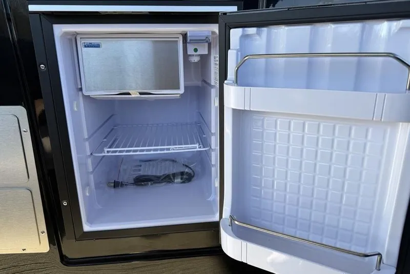 Slide: The Image of Open refrigerator in 2026 Premier 330 Escalante RV, showing empty shelves and door storage. - 58