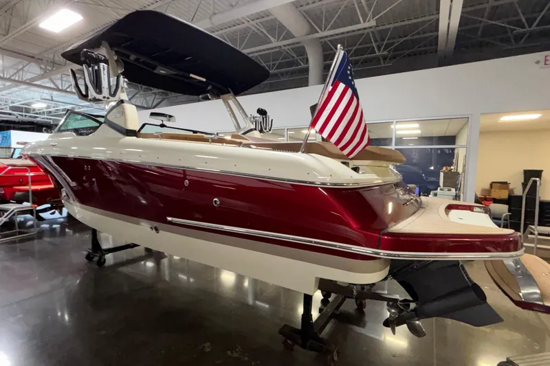 Slide: The Image of 2026 Chris-Craft Sportster 28 boat with American flag, displayed indoors. - 2
