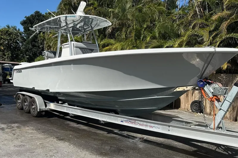 The Image of 2019 Contender 30 ST boat on trailer, surrounded by lush greenery. - 0