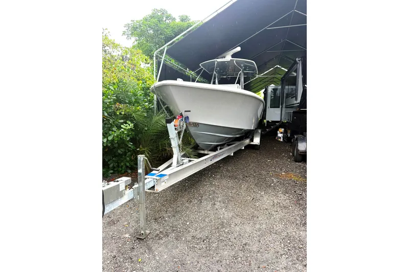Slide: The Image of 2019 Contender 30 ST boat on trailer under canopy, surrounded by greenery. - 4