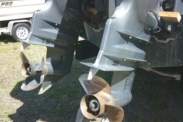 Slide: The Image of Twin outboard motors on a 2004 Grady White 27 Islander boat, resting on grass. - 15