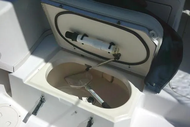 Slide: The Image of Livewell compartment on a 2004 Grady White 27 Islander boat, featuring a net and pump. - 31