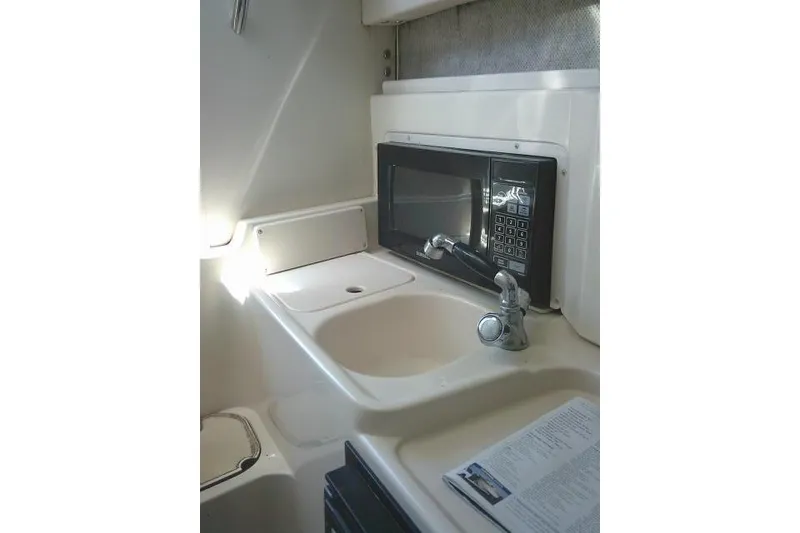 Slide: The Image of Compact kitchen area in a 2004 Grady White 27 Islander boat with sink and microwave. - 49