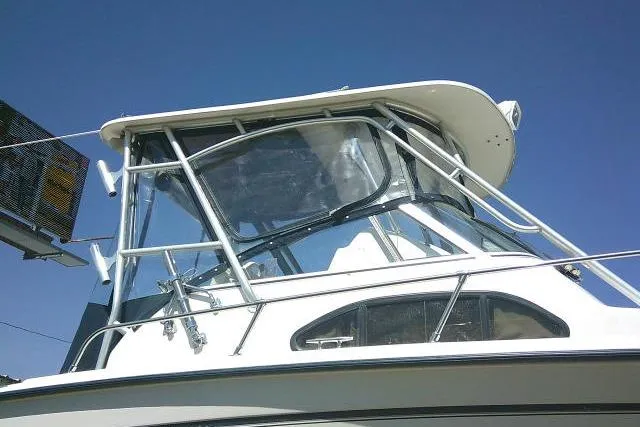 Slide: The Image of 2004 Grady White 27 Islander boat with clear enclosure and sturdy frame against blue sky. - 6