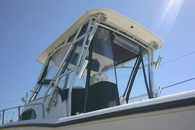 Slide: The Image of 2004 Grady White 27 Islander boat with clear enclosure under a bright blue sky. - 9