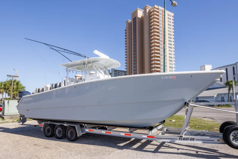 The Image of 2014 Freeman 33 boat on trailer, parked near tall buildings under clear blue sky. - 0