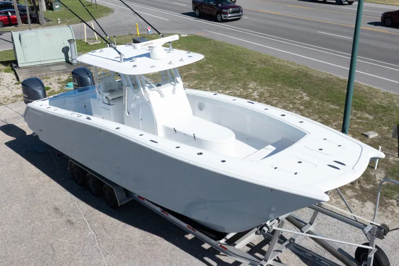 Slide: The Image of White 2014 Freeman 33 boat on trailer, parked near a road. - 1