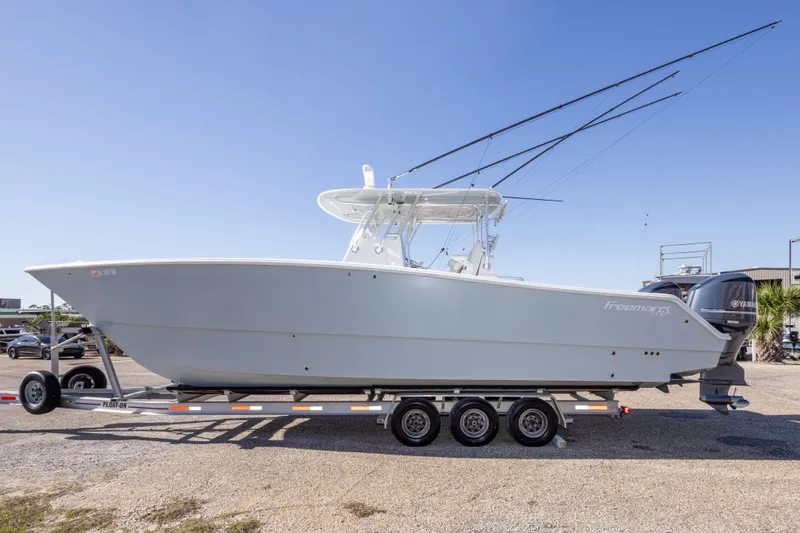 Slide: The Image of 2014 Freeman 33 boat on trailer with dual Yamaha engines, parked outdoors. - 14