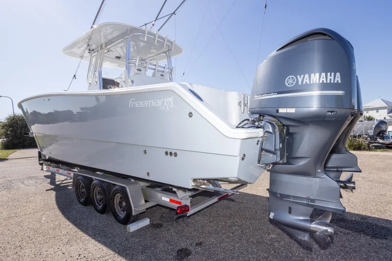 Slide: The Image of 2014 Freeman 33 boat with Yamaha engine on a trailer, parked outdoors. - 17