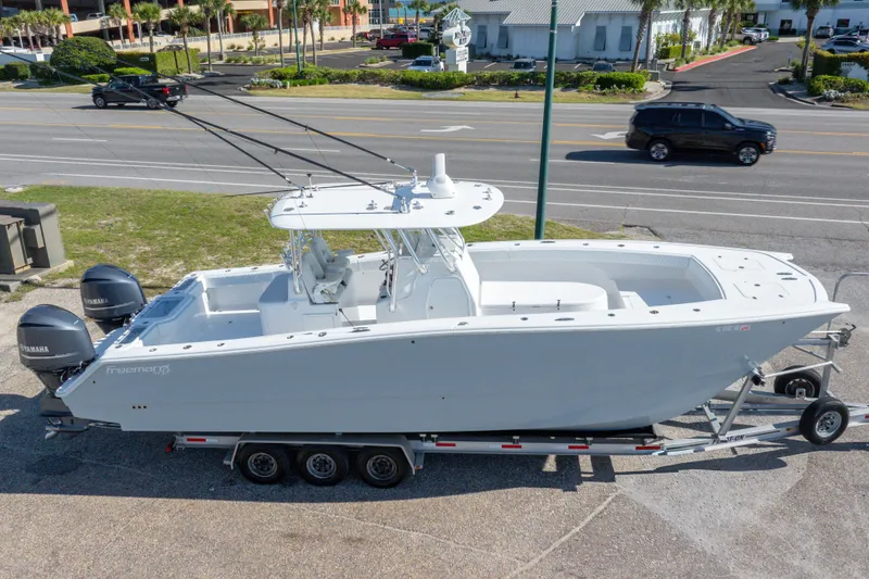 Slide: The Image of 2014 Freeman 33 boat on trailer with dual Yamaha engines, parked near a road. - 2