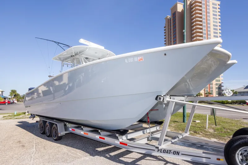 Slide: The Image of 2014 Freeman 33 boat on trailer, parked near tall building under clear blue sky. - 3