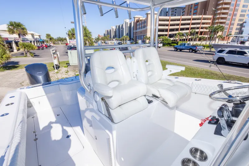 Slide: The Image of 2014 Freeman 33 boat interior with white seating and steering wheel, parked near a road. - 41