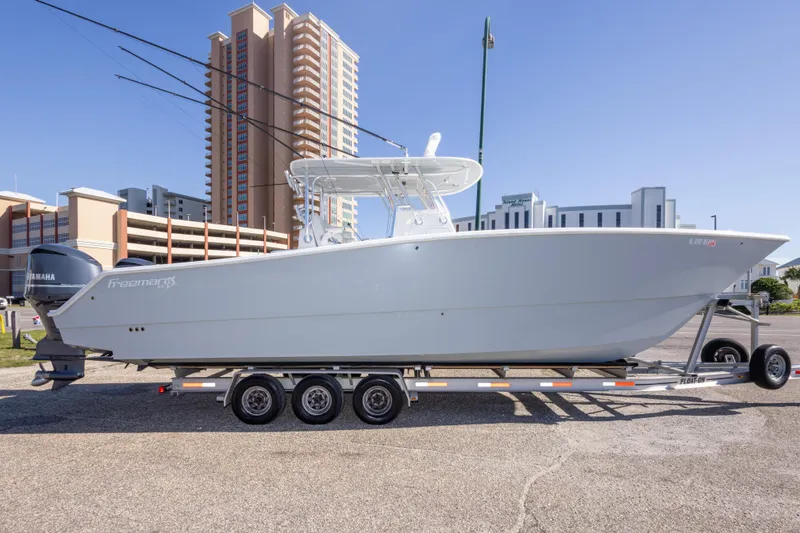 Slide: The Image of 2014 Freeman 33 boat on trailer, parked near tall buildings, clear sky. - 7