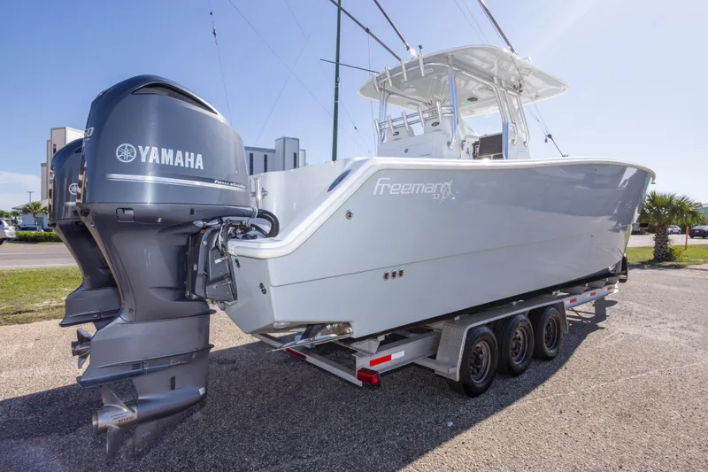 Slide: The Image of 2014 Freeman 33 boat with Yamaha engines on a trailer, parked outdoors. - 8