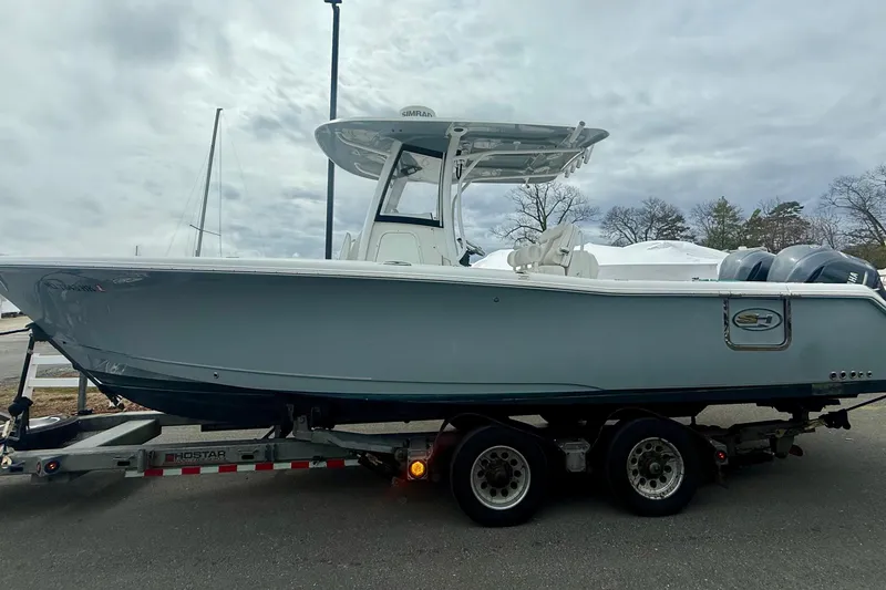 The Image of 2017 Sea Hunt Gamefish 30 boat on trailer, parked outdoors under cloudy sky. - 1