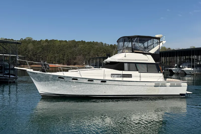 Slide: The Image of 1994 Bayliner 3888 MY Sedan yacht on calm water, surrounded by trees and docks. - 10