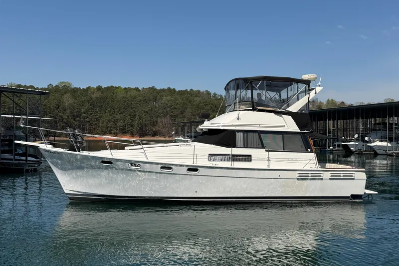 Slide: The Image of 1994 Bayliner 3888 MY Sedan yacht on calm water, surrounded by trees and docks. - 11