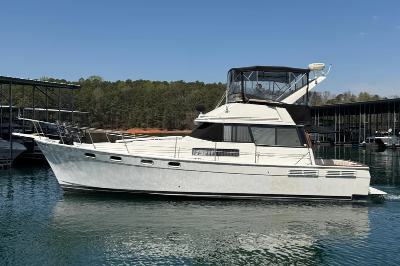 Slide: The Image of 1994 Bayliner 3888 MY Sedan yacht docked on a serene lake under clear skies. - 12