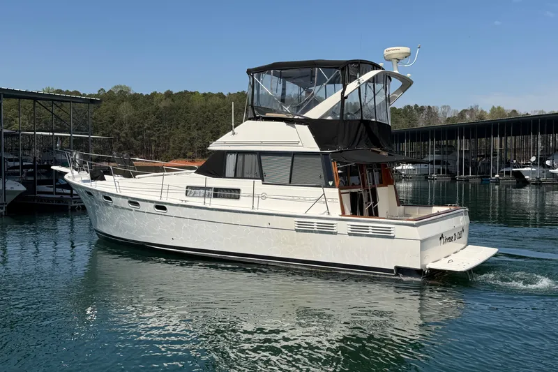 Slide: The Image of 1994 Bayliner 3888 MY Sedan cruising on a serene lake near a marina. - 15