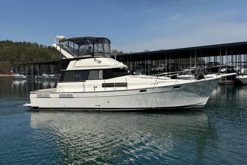 Slide: The Image of 1994 Bayliner 3888 MY Sedan yacht cruising on a serene lake near a marina. - 2