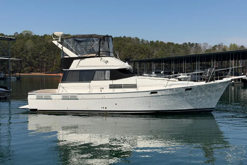 Slide: The Image of 1994 Bayliner 3888 MY Sedan yacht on calm water, surrounded by trees and docks. - 24