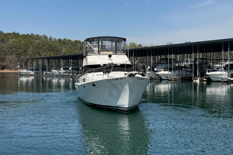 Slide: The Image of 1994 Bayliner 3888 MY Sedan cruising near marina with docked boats in background. - 3
